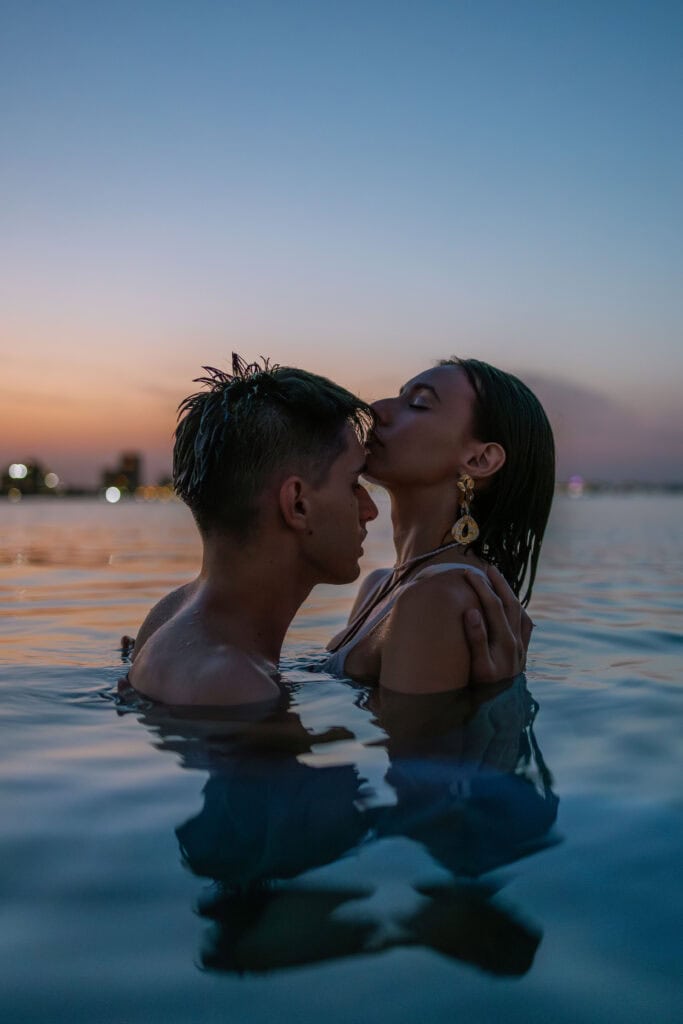 Couple photoshoot on the beach during the sunset in Spain, kissing in the water